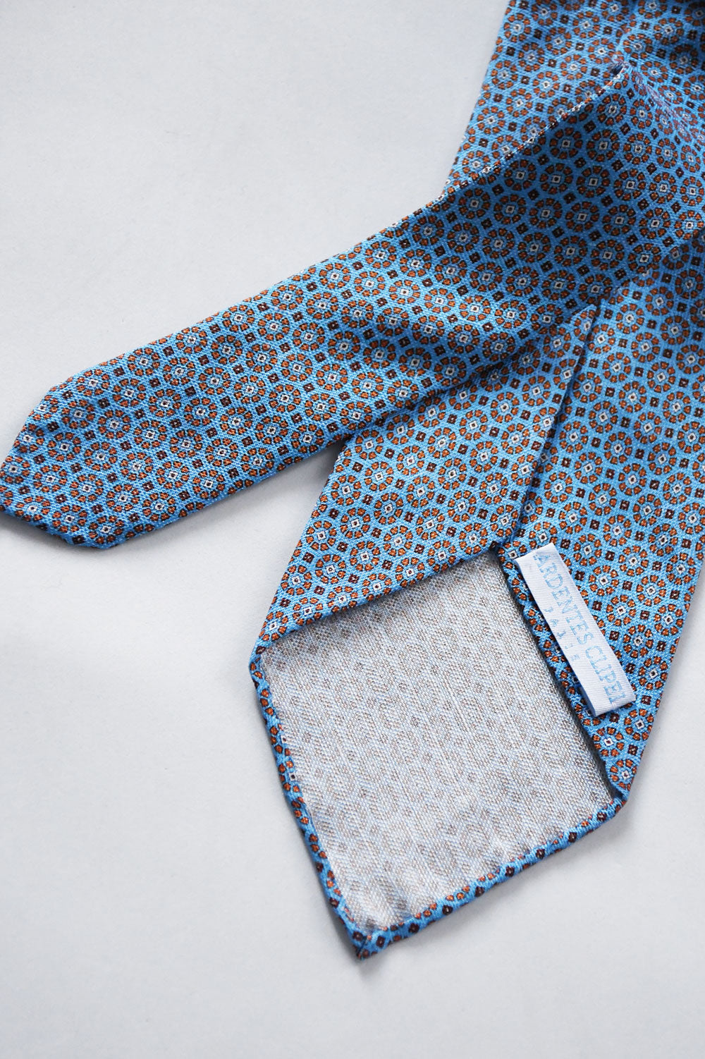 Blue sky tie with geometric pattern in silk and linen by Ardentes Clipei, showcasing its elegant design and vibrant color.