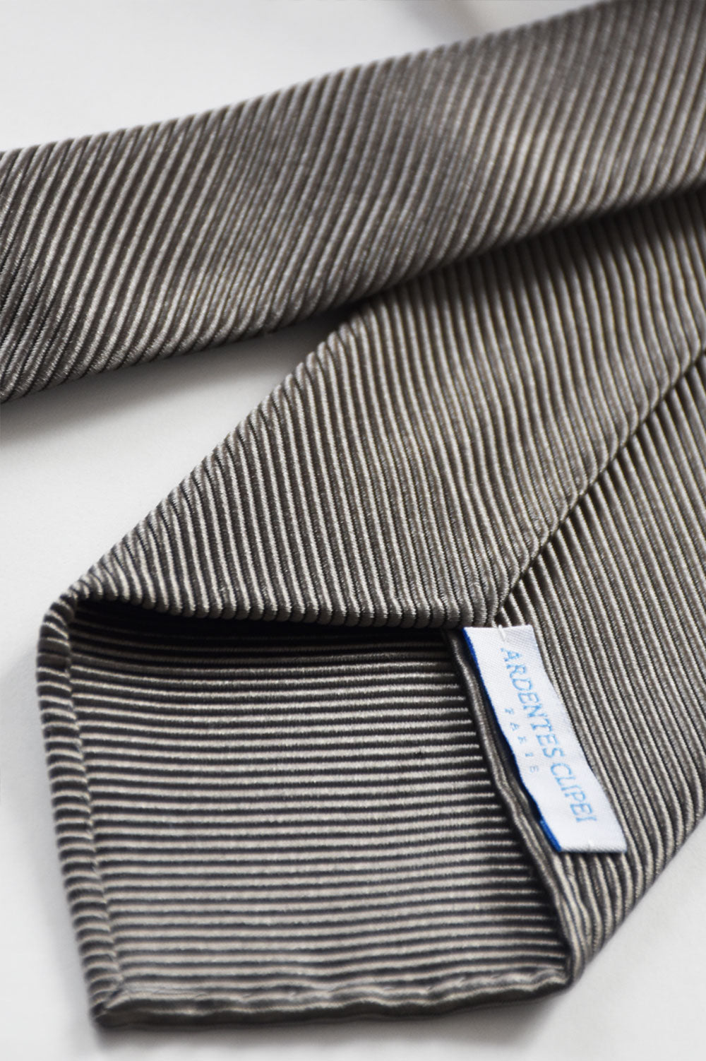 Gray silk twill tie with subtle branding details from Ardentes Clipei, showcasing its textured fabric and elegant design.