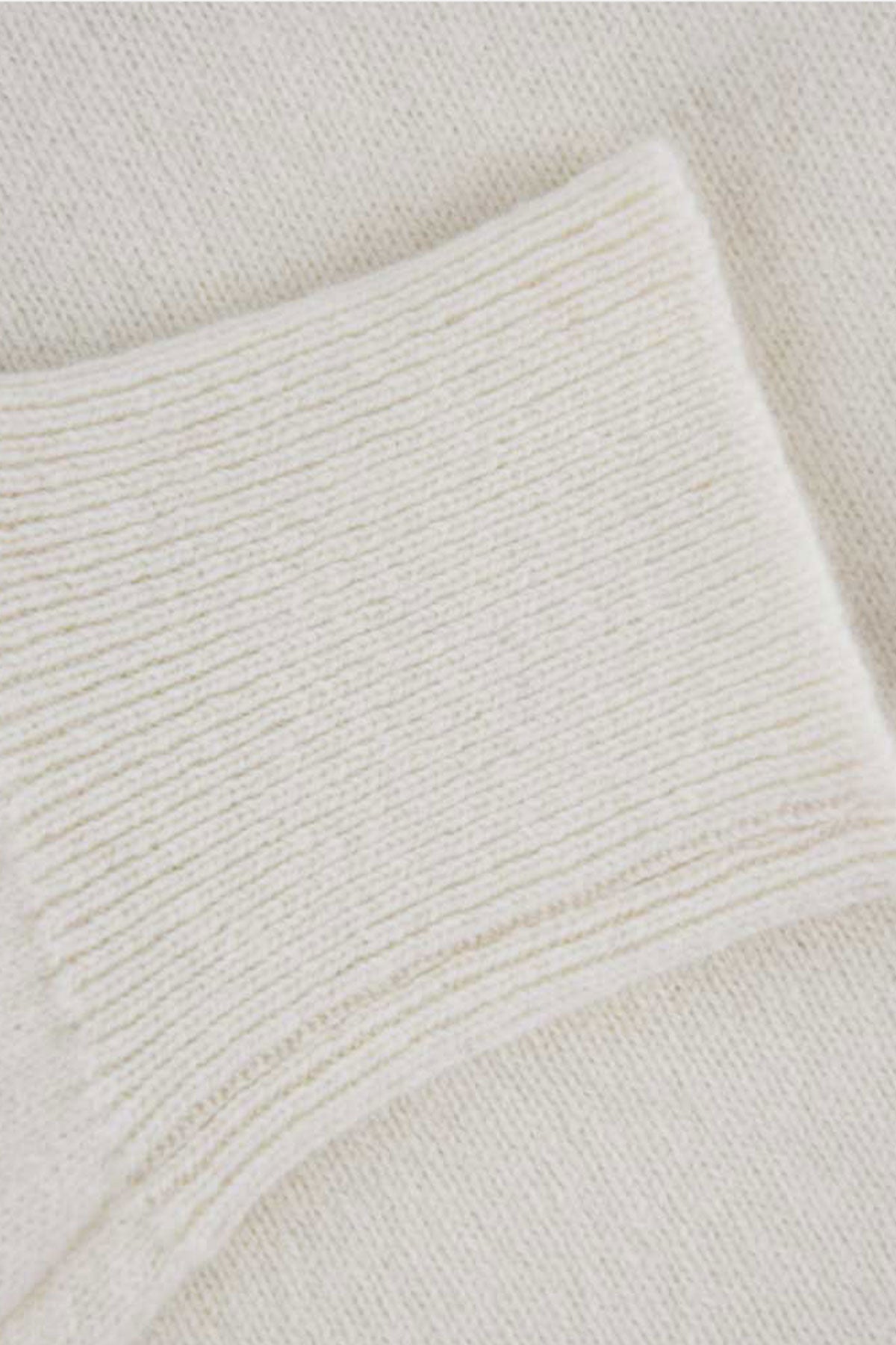 Cream-colored Ardentes Clipei wool turtleneck sweater, lightweight knit, close-up of soft, cozy fabric with ribbed collar.