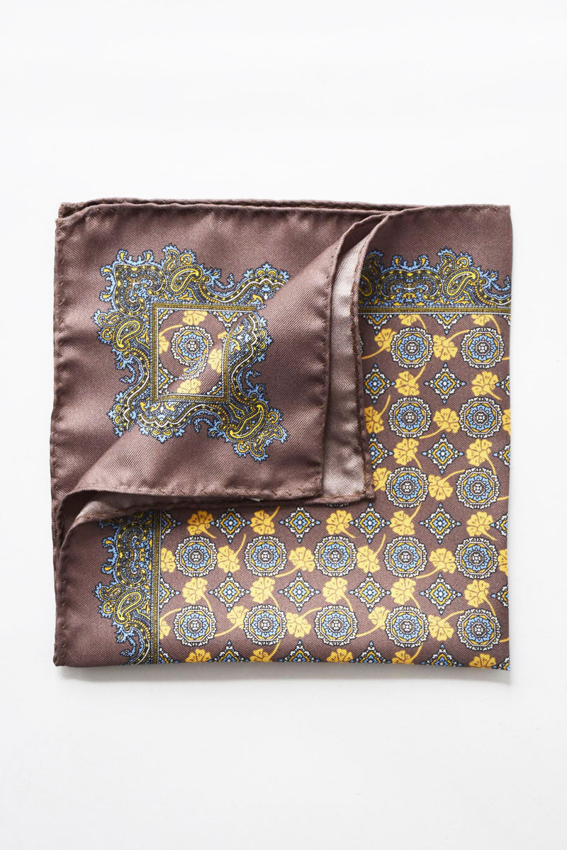Taupe silk pochette with medallion and paisley motifs by Ardentes Clipei, featuring elegant design and intricate pattern details.