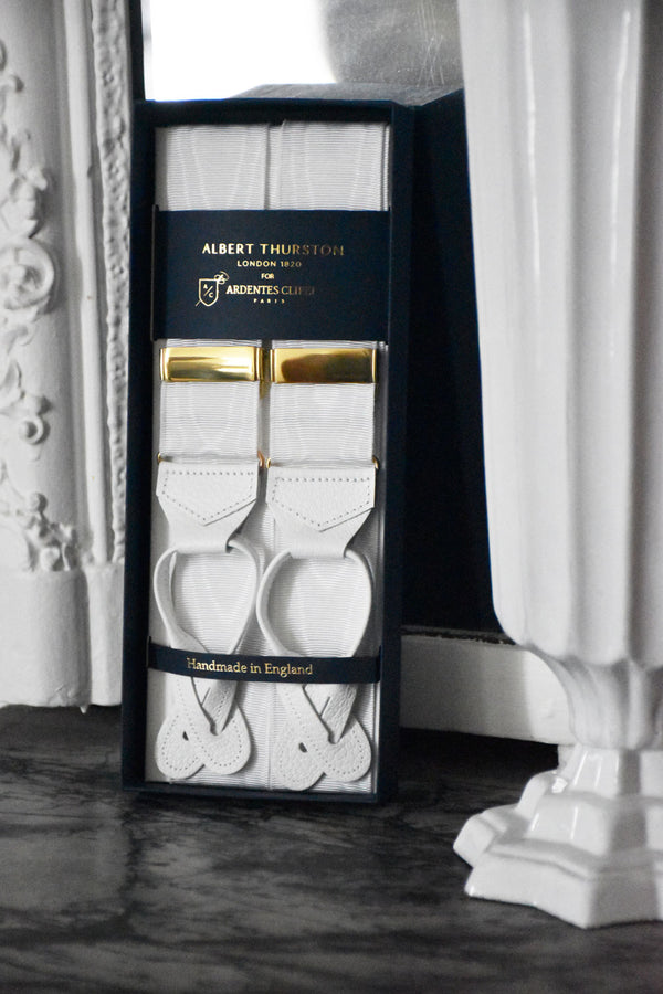 White moiré suspenders by Albert Thurston, featuring elegant gold accents, worn with formal attire.