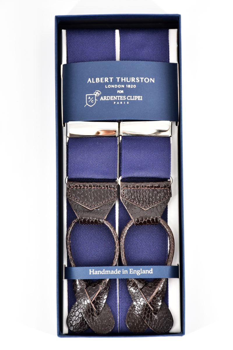 Pair of navy blue Albert Thurston suspenders with adjustable straps and classic design, worn over a dress shirt.
