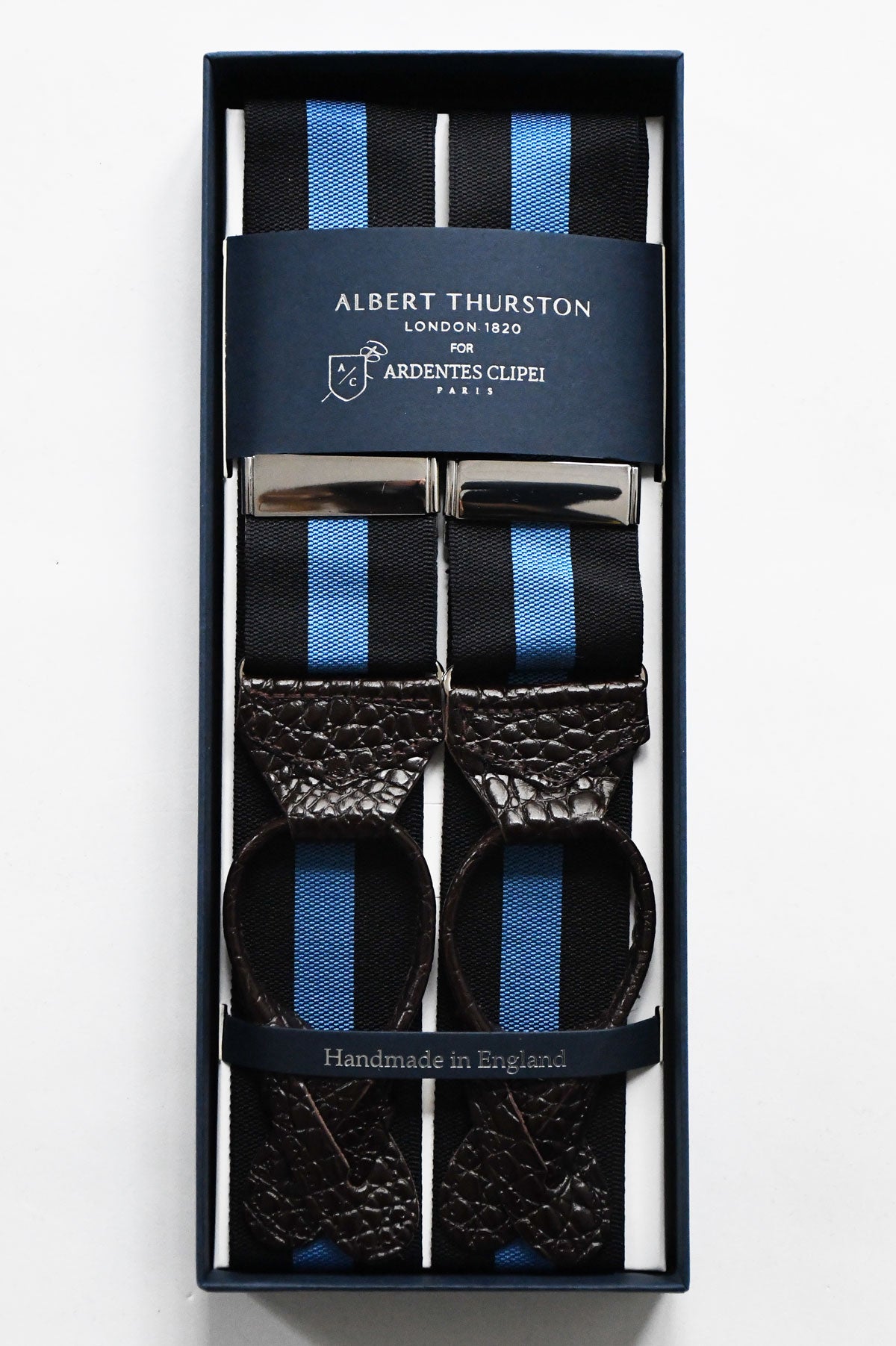 Blue and black striped suspenders by Albert Thurston, featuring adjustable straps and classic design with metal clasps.