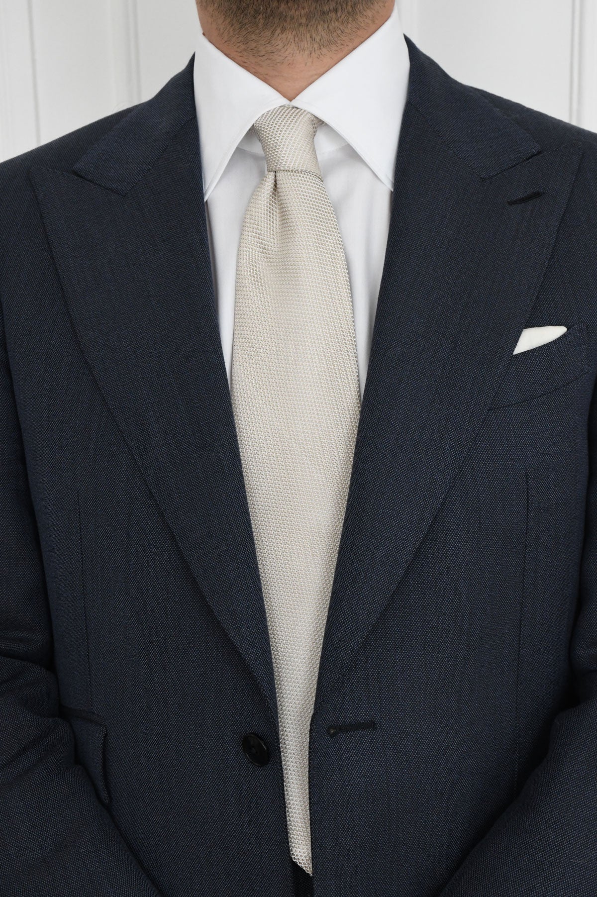 Beige crème silk Grenadine tie from Ardentes Clipei, shown draped over a white shirt with semi-spread collar.
