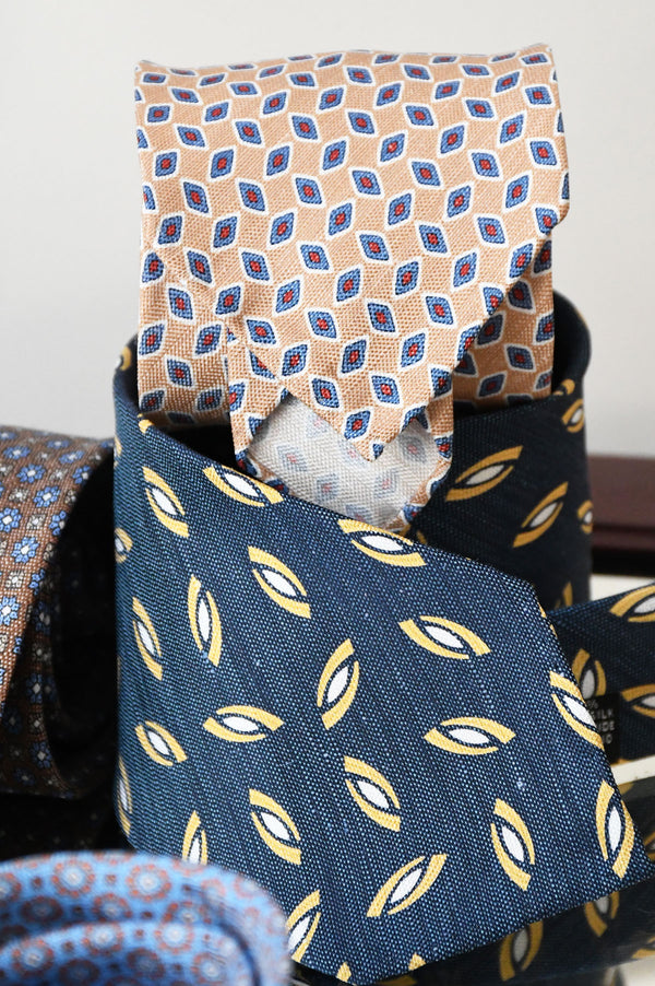 Beige tie with geometric pattern in silk and linen by Ardentes Clipei, showing detailed fabric texture and elegant design.