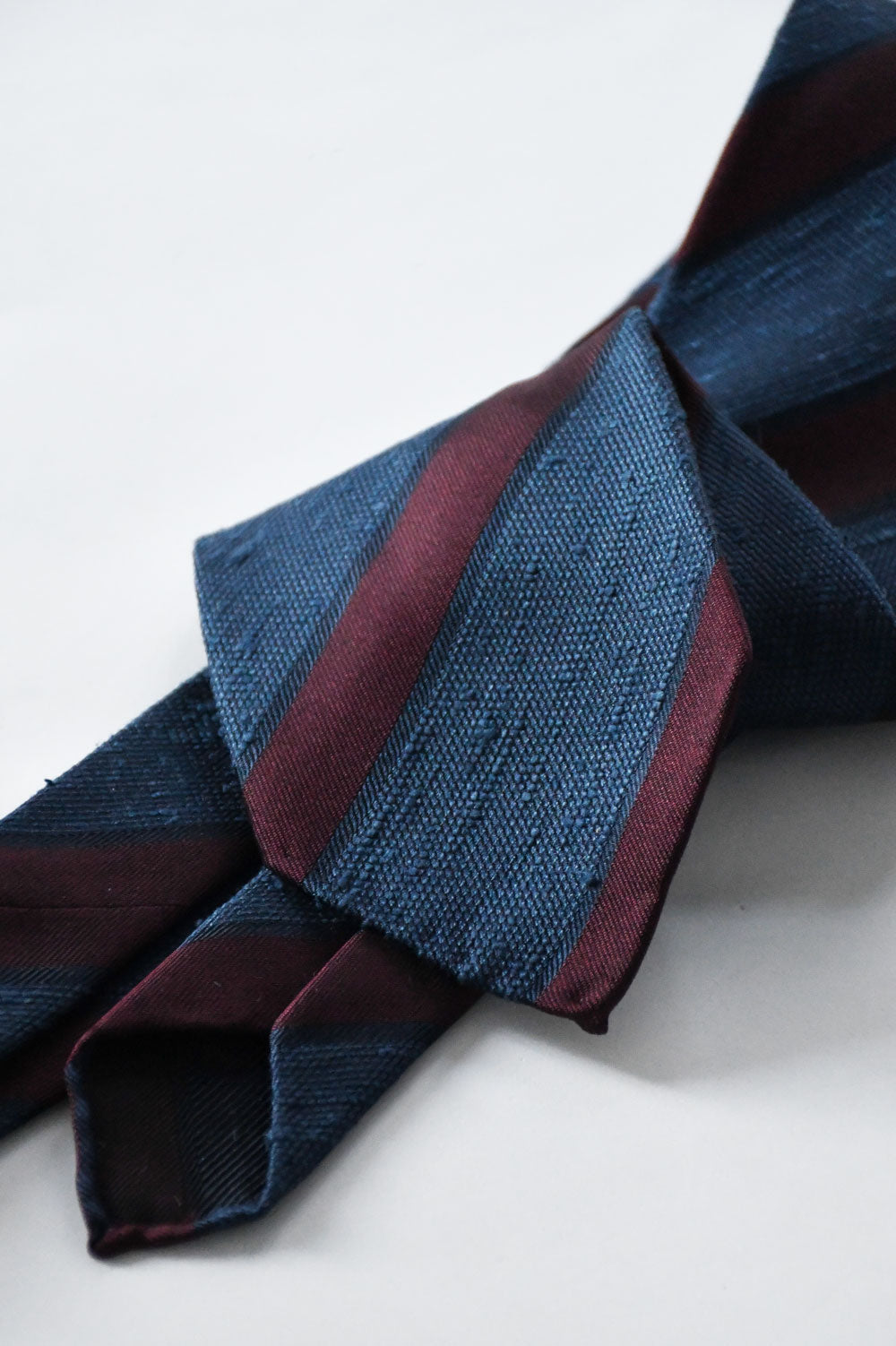 Blue denim and Bordeaux shantung club tie by Ardentes Clipei, featuring a textured fabric and classic design.