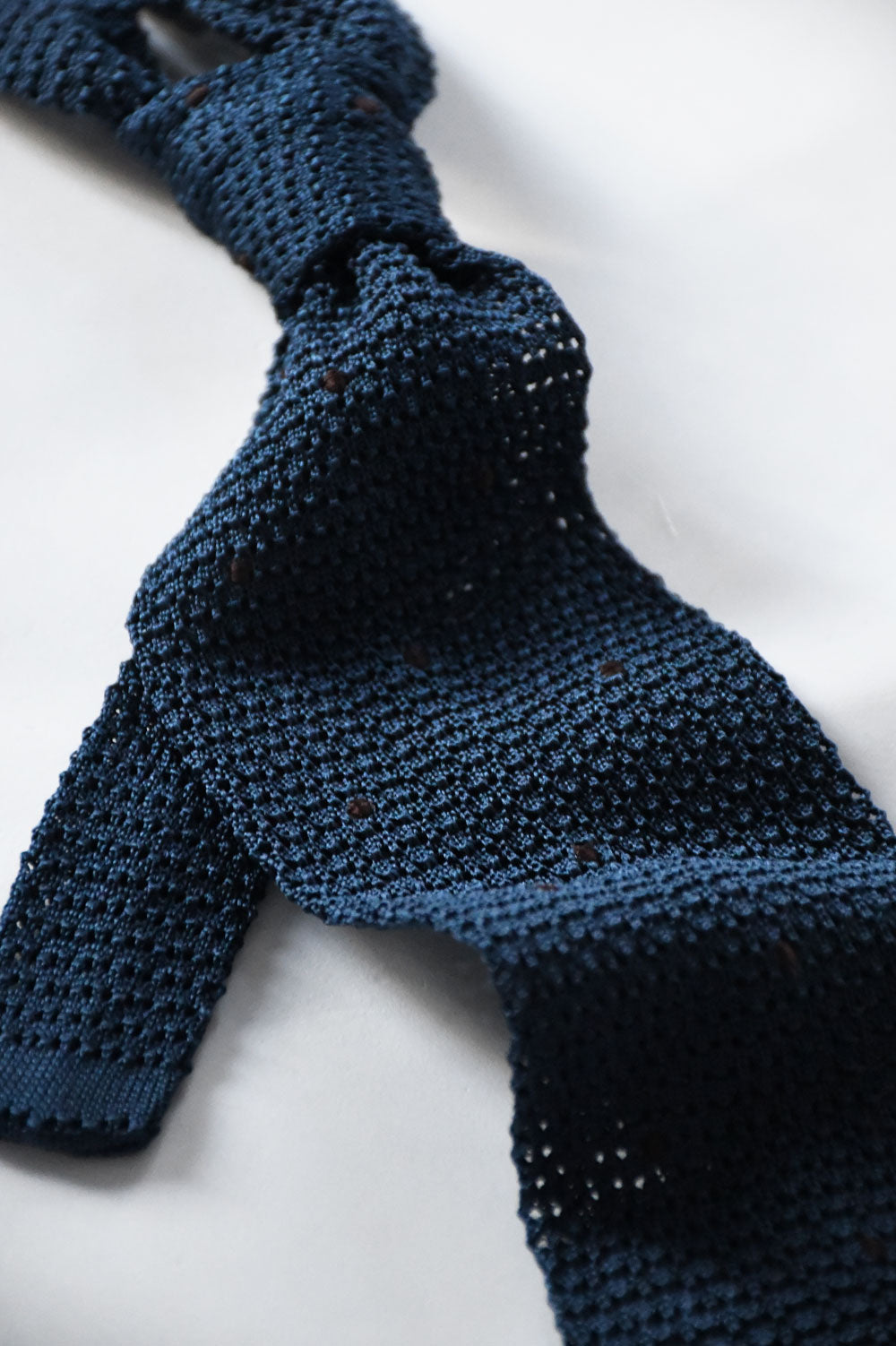Blue petrol knit tie with dark brown polka dots from Ardentes Clipei, close-up showing textured fabric and pattern details.