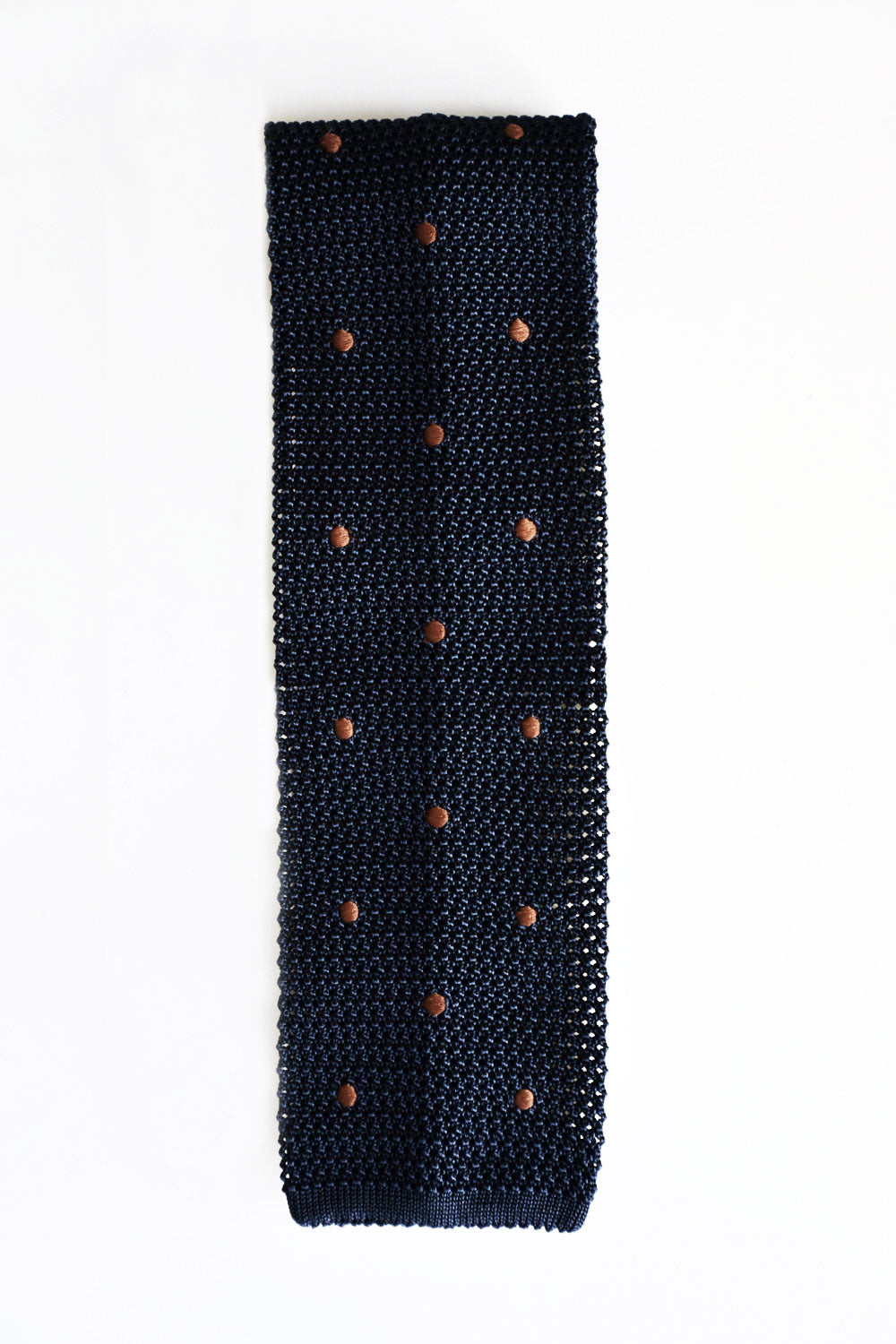 Blue knitted tie with brown polka dots from Ardentes Clipei, showcasing detailed texture and classic pattern.