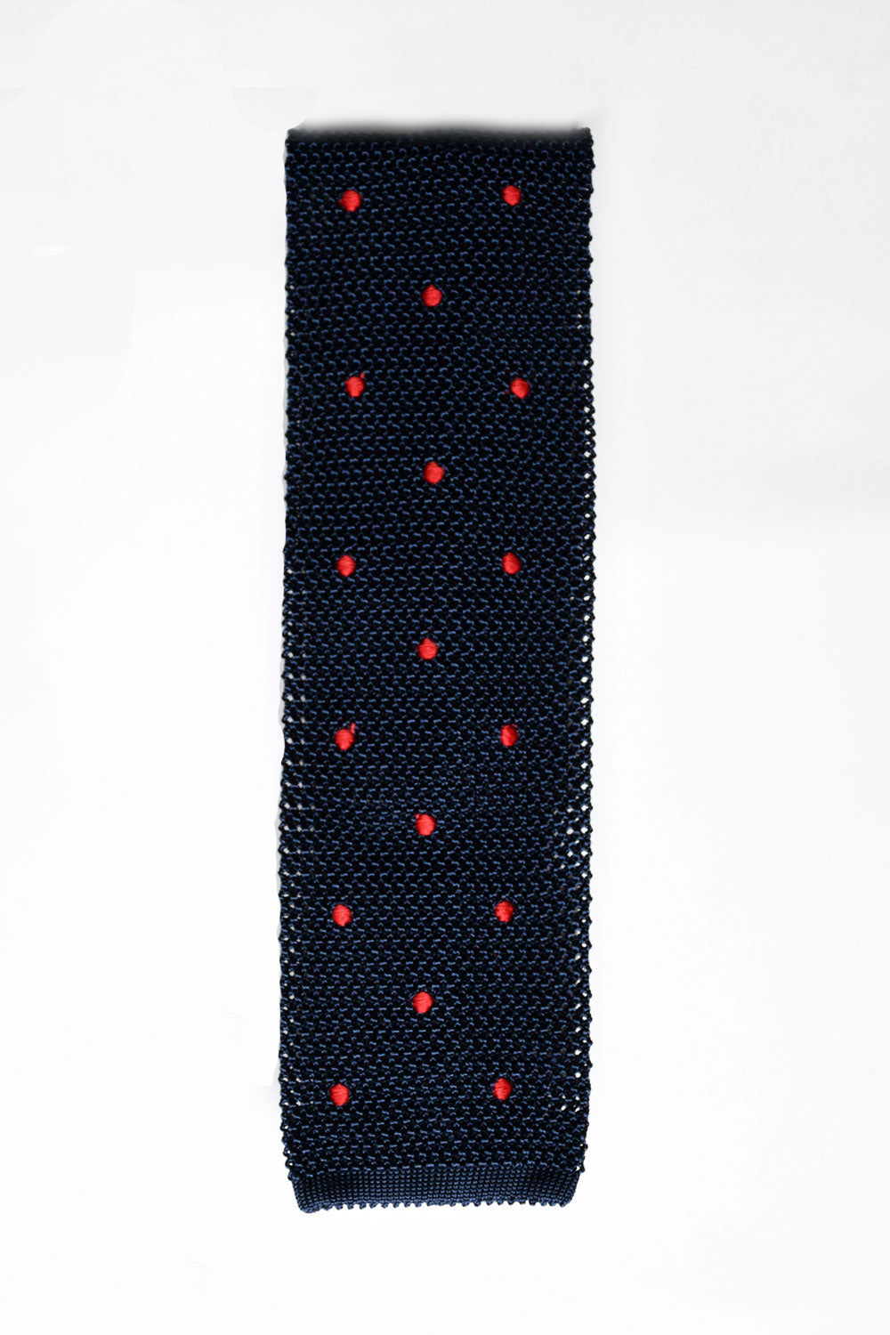 Blue knitted tie with red polka dots from Ardentes Clipei, showing close-up of fabric and pattern.