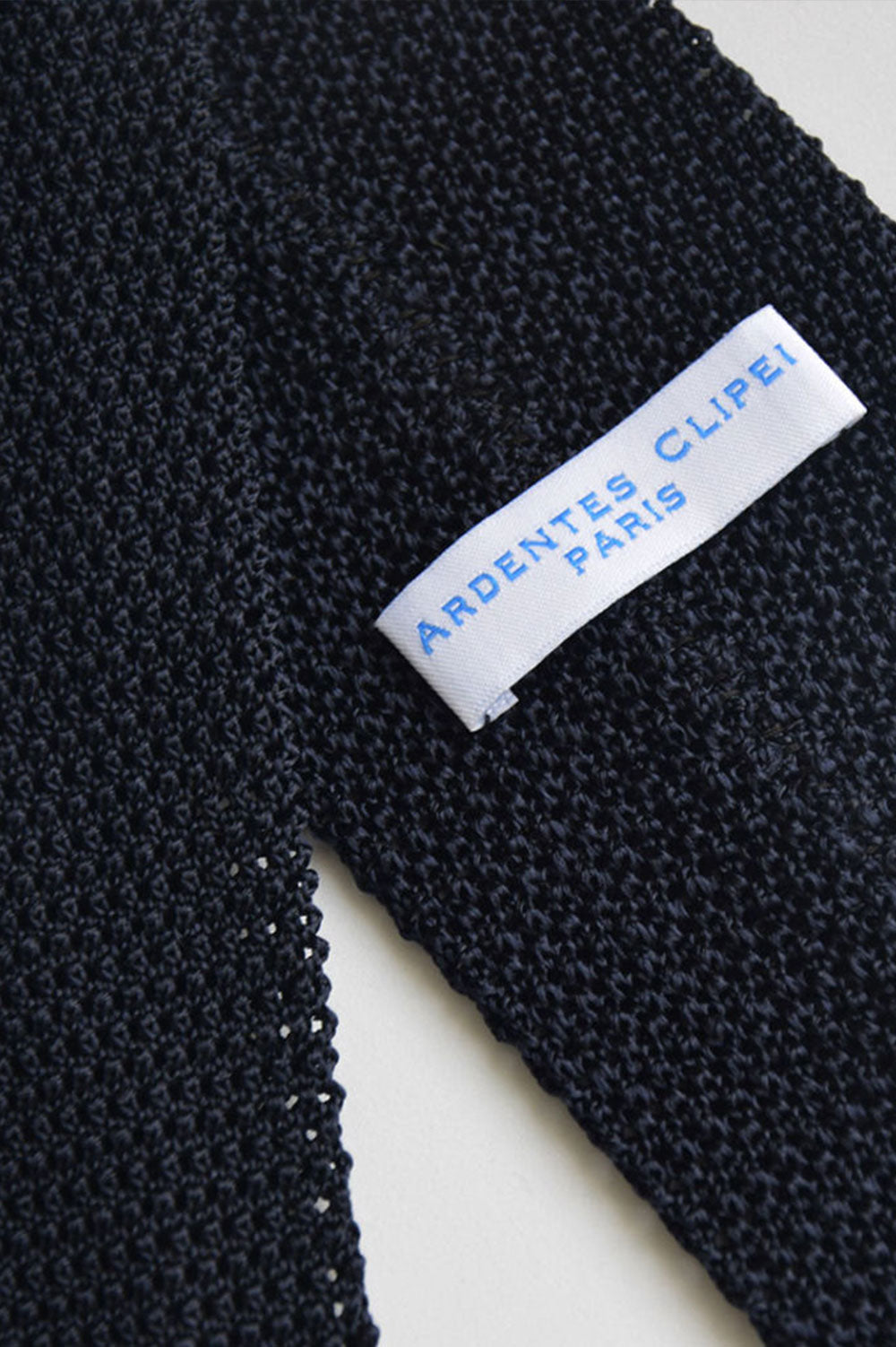 Blue navy knitted tie from Ardentes Clipei, close-up of textured fabric and classic design for men's formal wear.