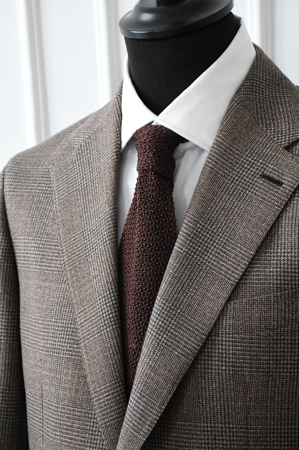 Brown knitted tie by Ardentes Clipei, close-up of textured fabric and tailored design for stylish men's accessory.