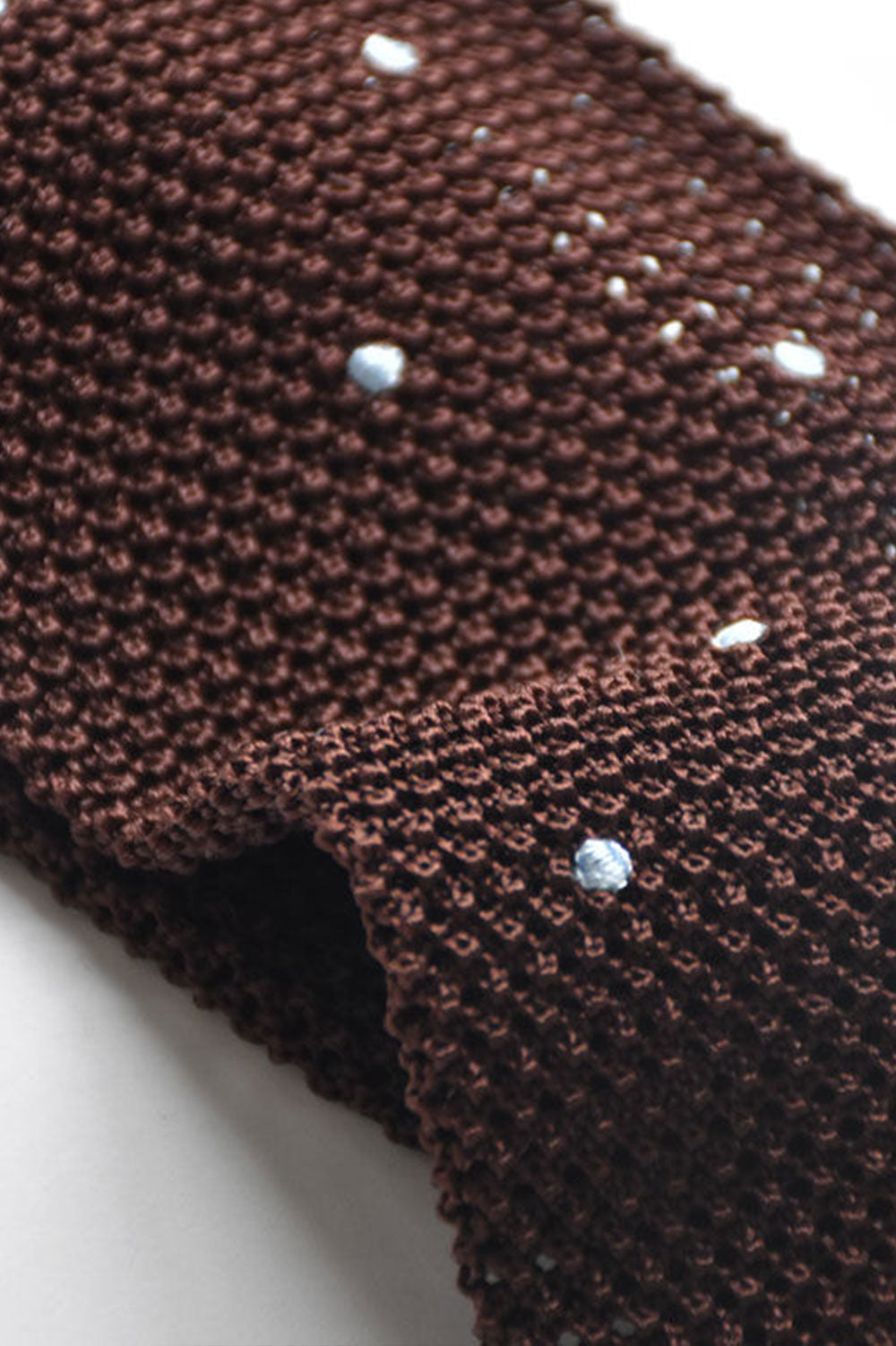 Brown knit tie with sky blue polka dots from Ardentes Clipei, showcasing textured fabric and playful pattern.