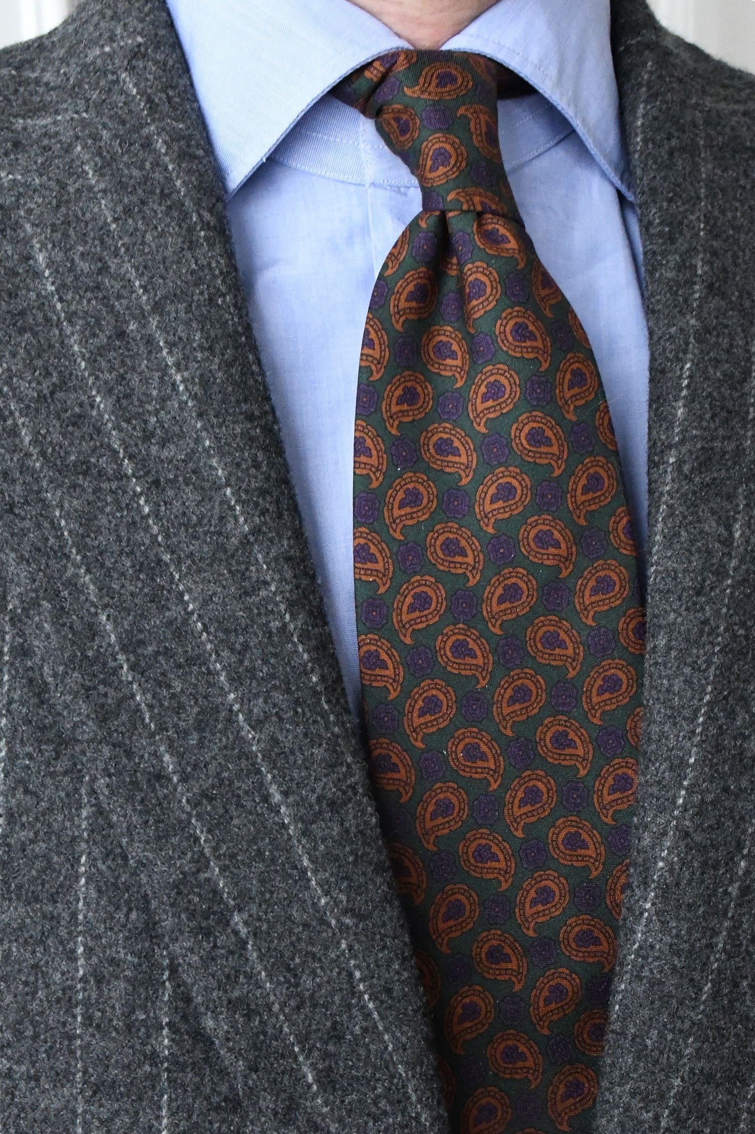 Green cravate with rust-colored paisley pattern by Ardentes Clipei, showcasing intricate design on smooth fabric.