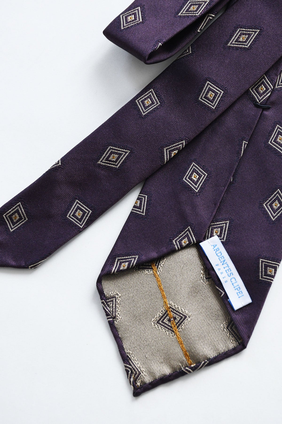 Violet silk jacquard tie with diamond motif by Ardentes Clipei, showcasing intricate woven pattern and elegant craftsmanship.