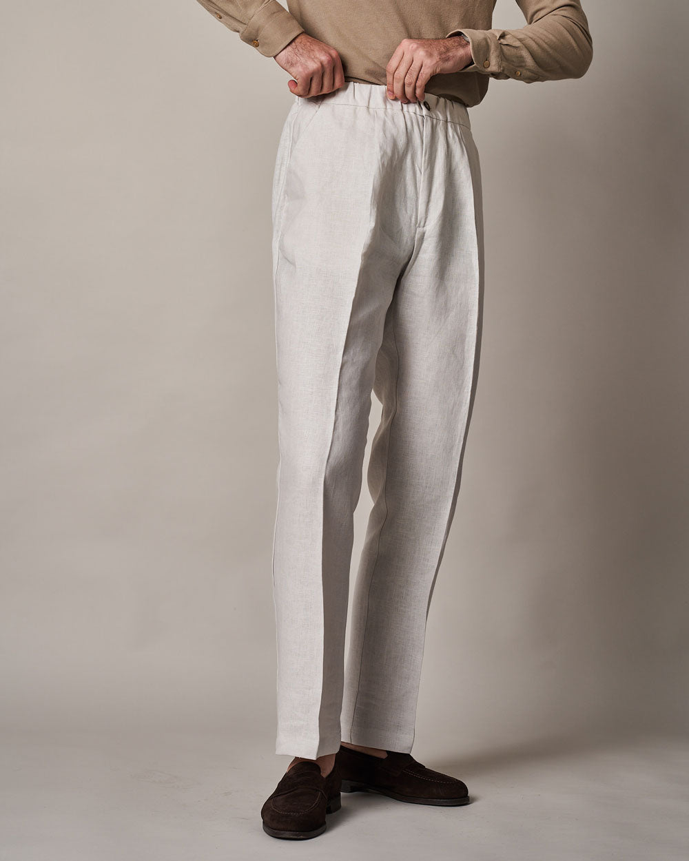 Beige Irish linen casual pants by Ardentes Clipei, featuring a relaxed fit and natural stone color, displayed on a model.