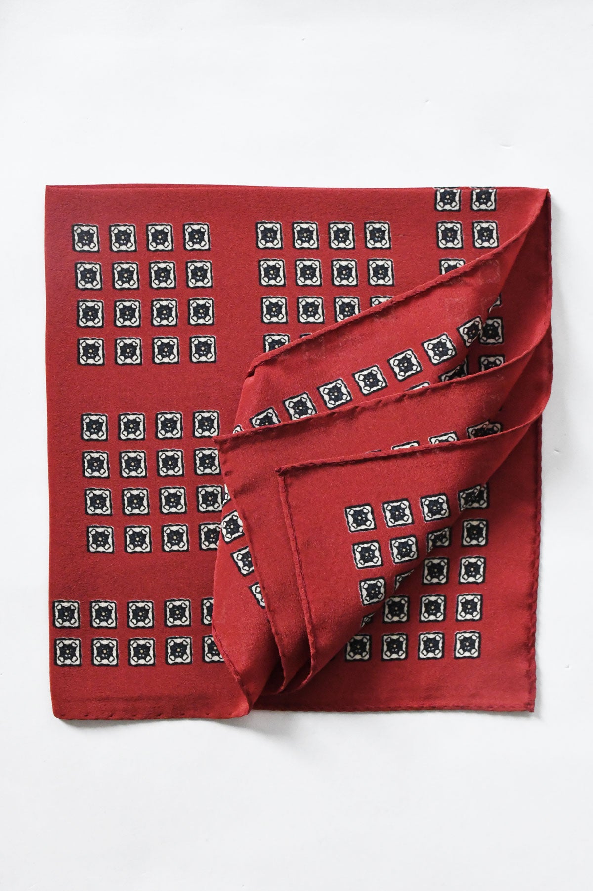 Red pochette by Ardentes Clipei featuring a geometric and floral motif, showcasing vibrant design and elegant craftsmanship.