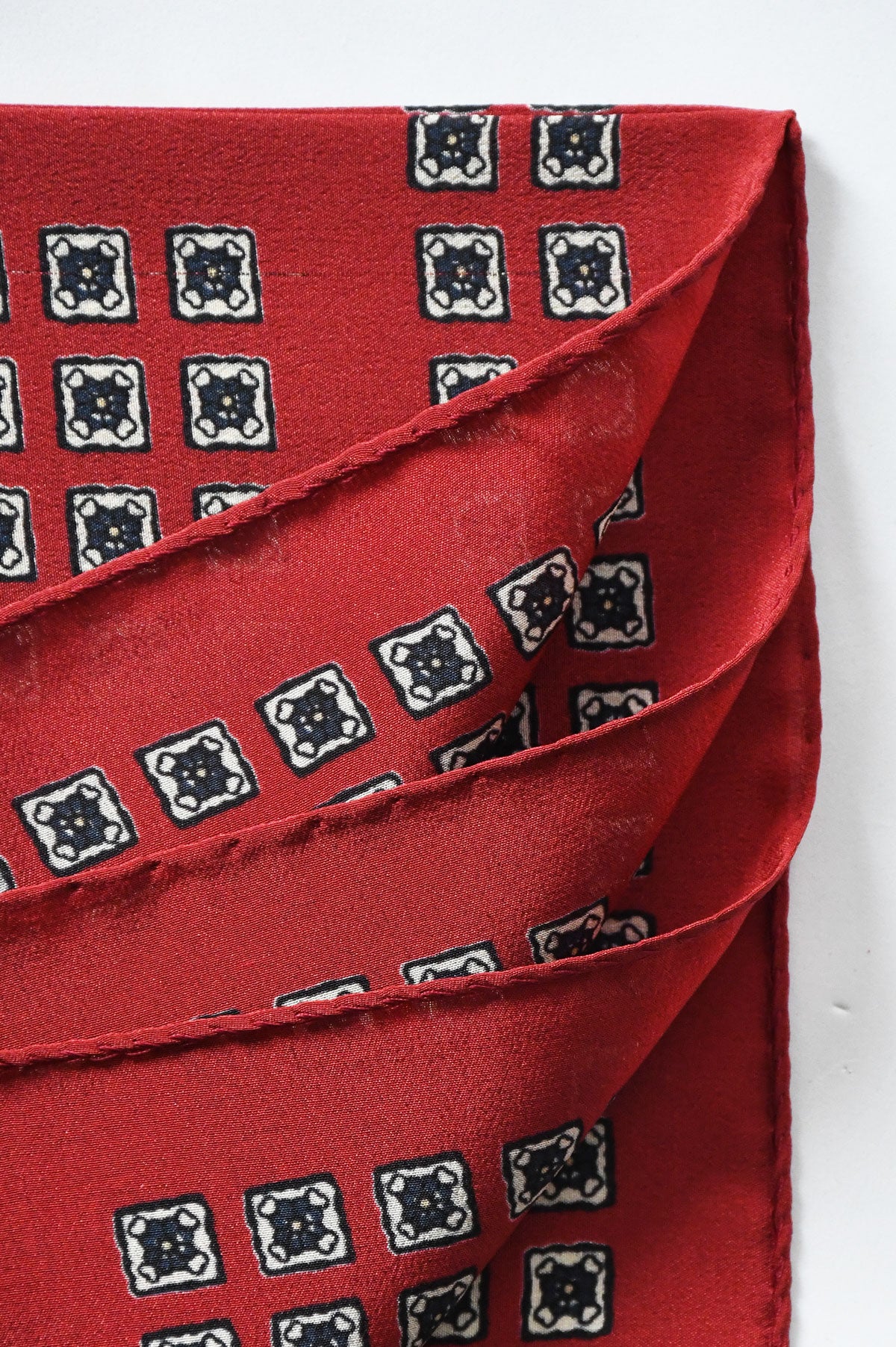 Red Ardentes Clipei pochette with geometric and floral motif, featuring vibrant patterns and elegant design.
