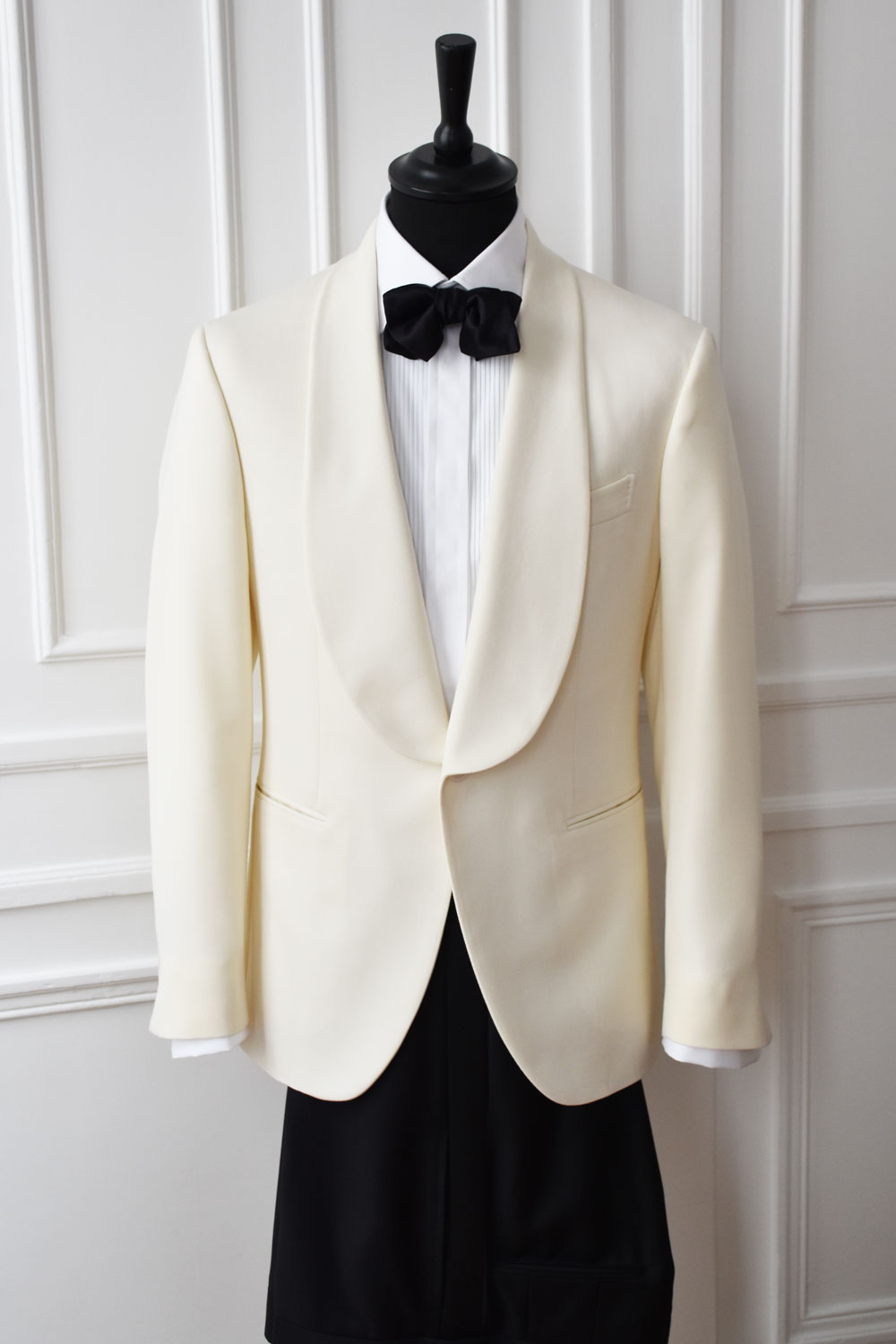 Veste de smoking blanche crème pour mariage, col châle, nœud papillon noir et chemise plissée sur mannequin